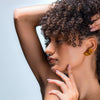 1970s Retro Ribbon Earrings in Gold, worn by a beautiful black model with big 1970s hair